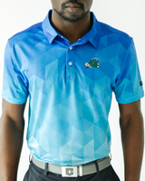 A man wearing a blue and light blue geometric patterned short-sleeve polo shirt with a small green and white alligator logo on the left chest, paired with a gray belt and dark pants.