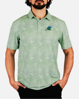 A man wearing a light green short-sleeve polo shirt with an all-over tropical leaf pattern and a small embroidered logo on the left chest, paired with black pants against a light gray studio background.