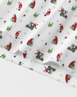 White fabric with a repeating Christmas-themed print featuring Santa Claus, golf carts, trees, and gift boxes, shown draped diagonally.
