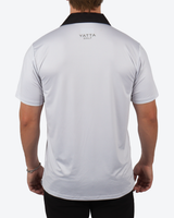 Back view of a man wearing a white short-sleeve polo shirt with a black collar and 'YATTA GOLF' printed in black on the upper back, against a light gray background.