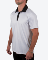 A man wearing a white short-sleeve polo shirt with a black collar and black placket, shown from the side against a light gray studio background.